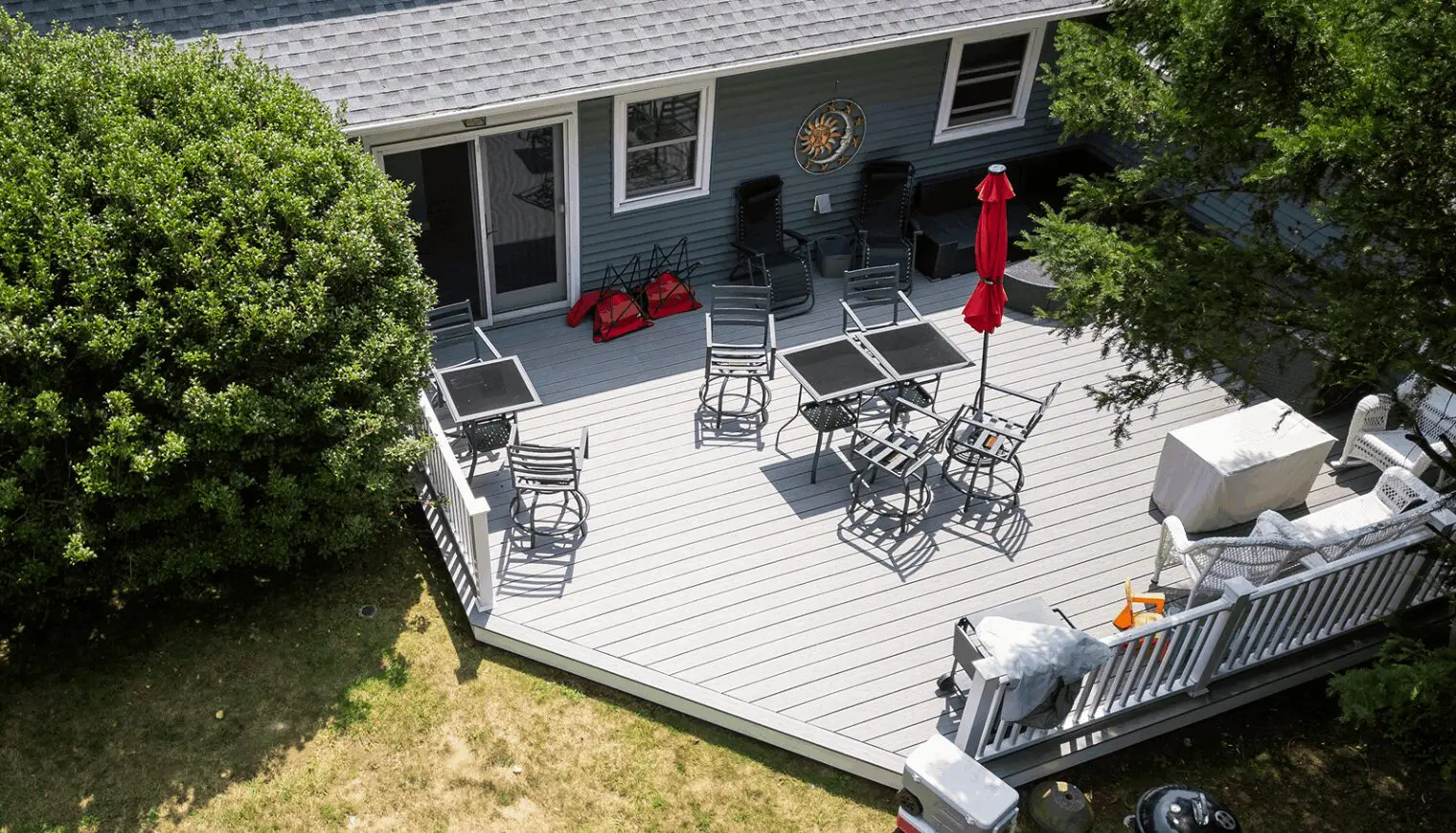 Spacious backyard deck with outdoor furniture and a red umbrella.