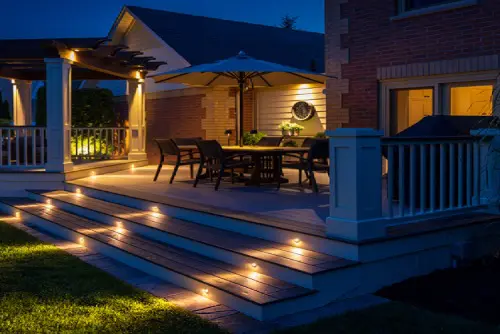 Nighttime lit backyard deck with outdoor dining
