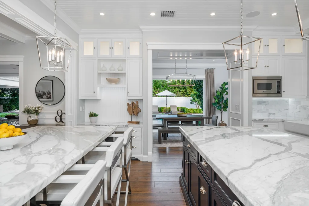 Bright modern kitchen with white marble countertops and stools.