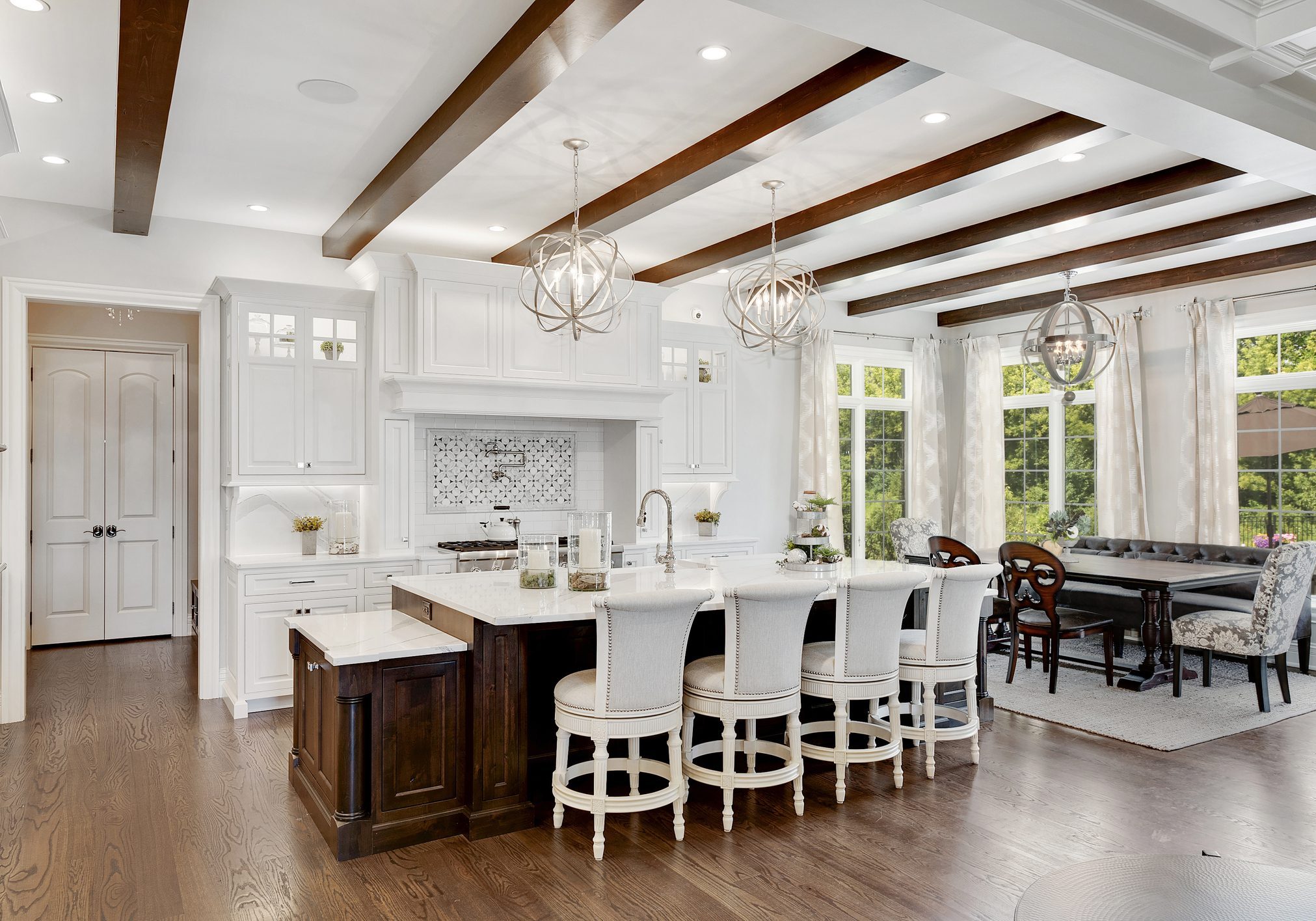 Bright kitchen with white cabinetry and wooden beam ceiling.