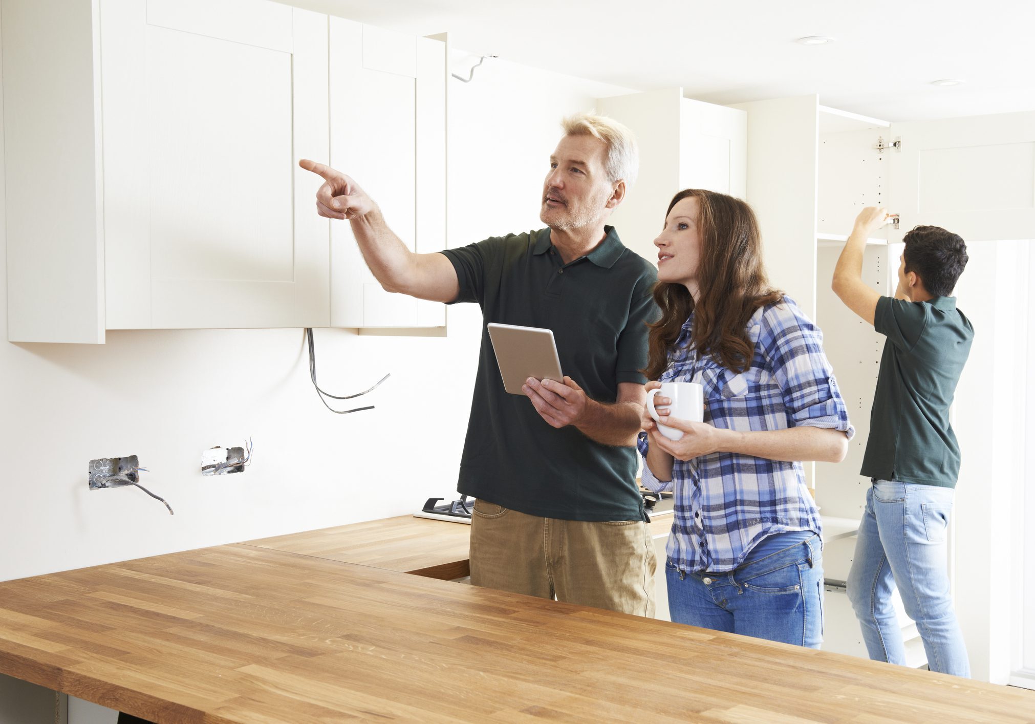 Couple discussing kitchen cabinets with a tablet.